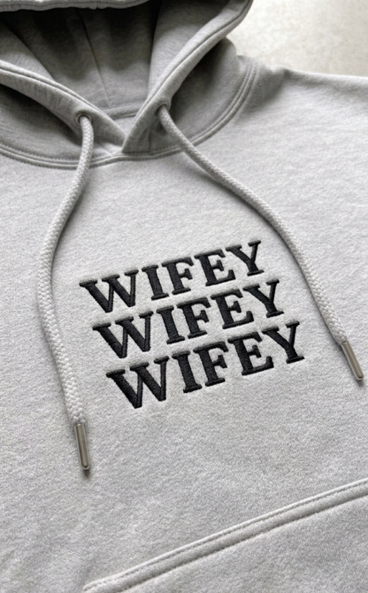 Gray hoodie with 'WIFEY WIFEY WIFEY' text on a plain background