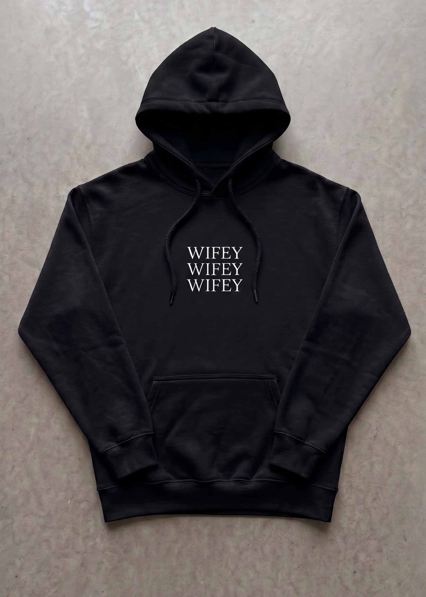 Black hoodie with 'WIFEY' text on a gray surface