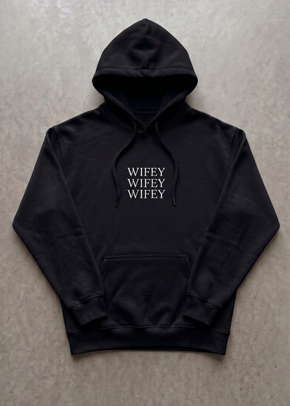 Black hoodie with 'WIFEY' text on a gray surface