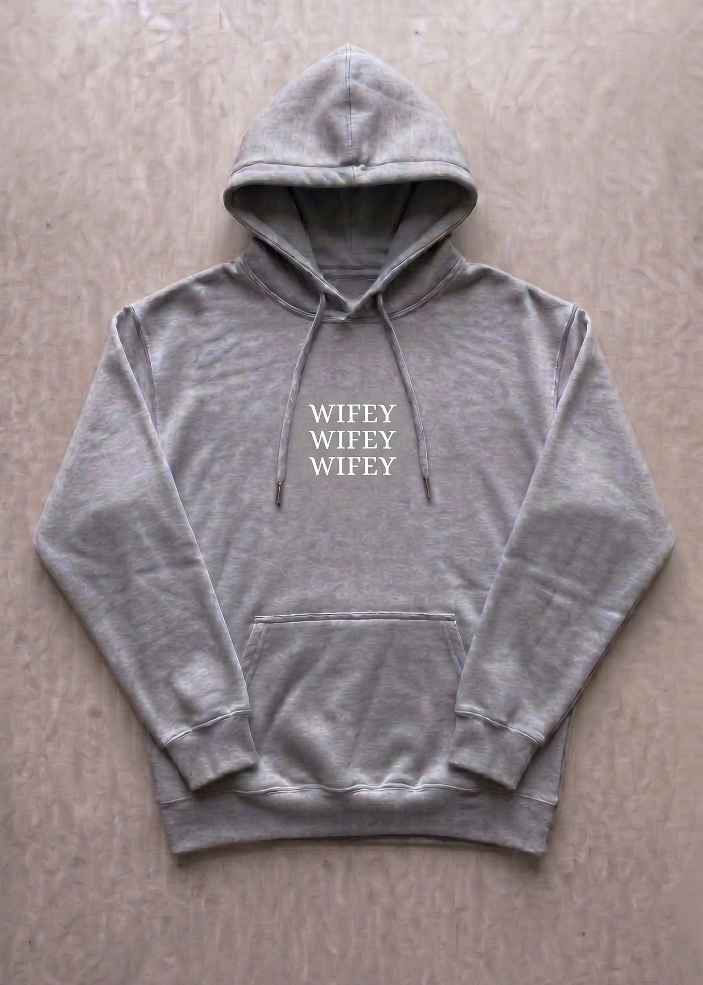 Gray hoodie with 'WIFEY' text on a beige surface