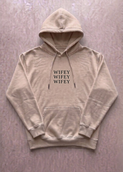 Beige hoodie with 'WIFEY' text on a light pink background