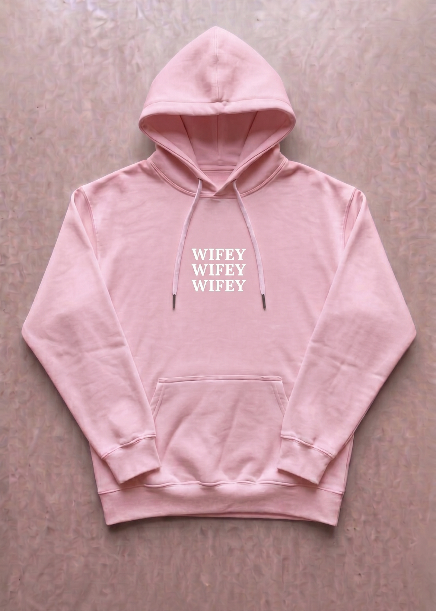 Pink hoodie with 'WIFEY' text on a beige background